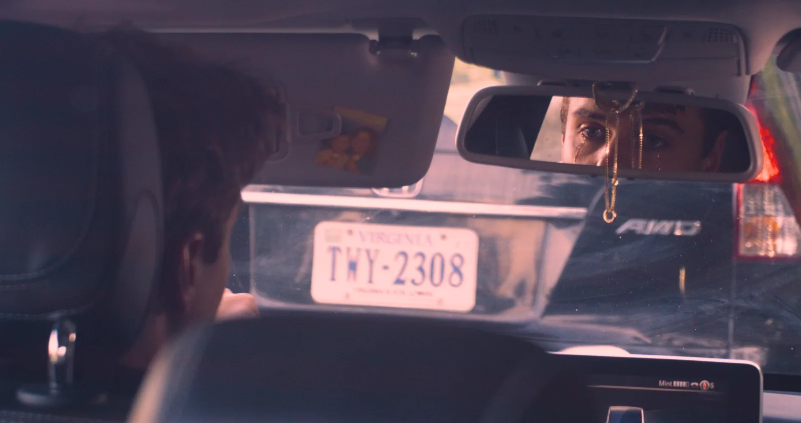 A man’s eyes reflected in his rearview mirror during a traffic stop