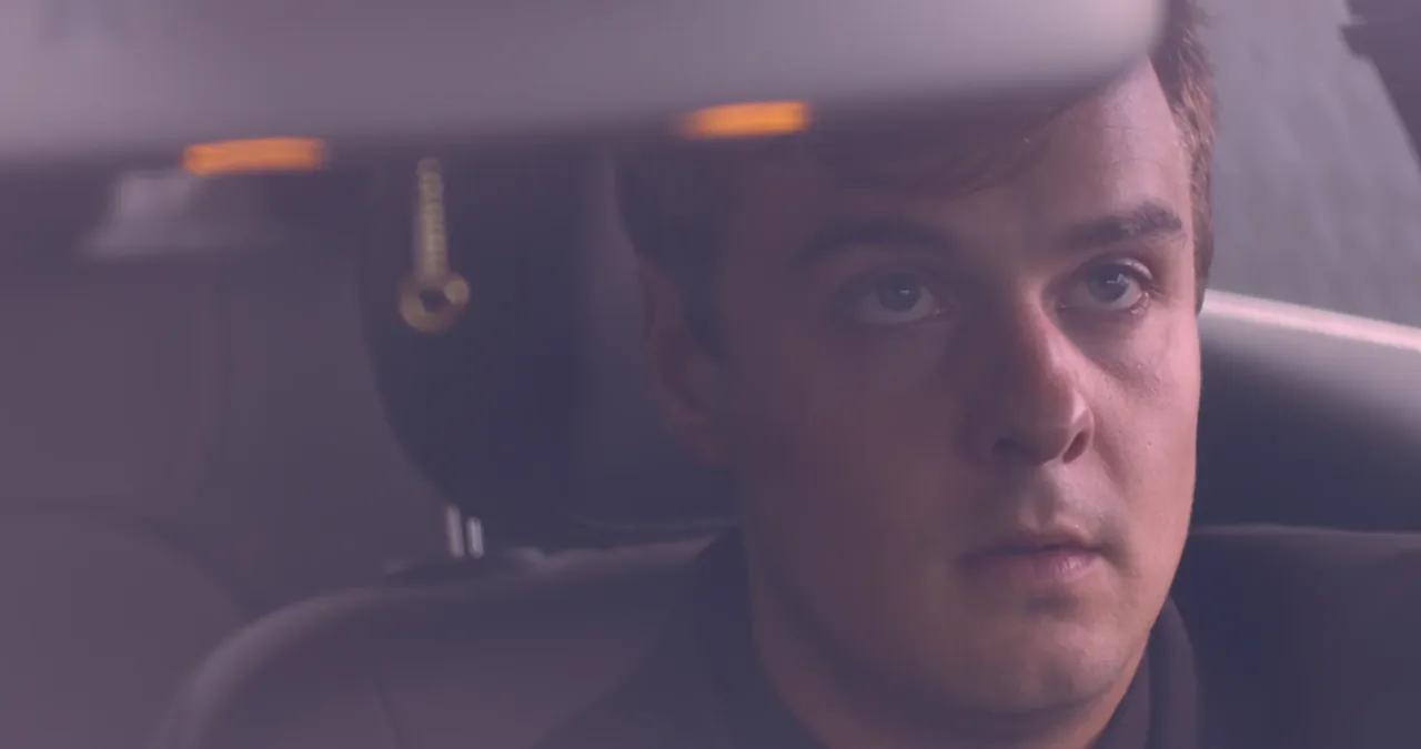 A grieving man seen through the windshield of his car